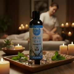 Bottle of 'Our Life' Menthol Fire & Ice Massage Oil on a tray with candles and ice cubes in a relaxing setting.