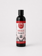 A bottle of Our Life CBD Pain Relief Massage Oil on a light gray background. The bottle is black with a black cap and features a white and red label with a mountain graphic.