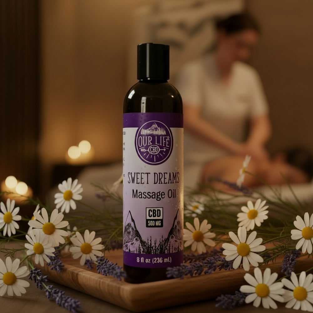 Bottle of 'Sweet Dreams' massage oil with lavender and daisies on a wooden board.