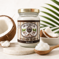 Jar of CBD coconut oil with a spoonful of oil and coconuts in the background