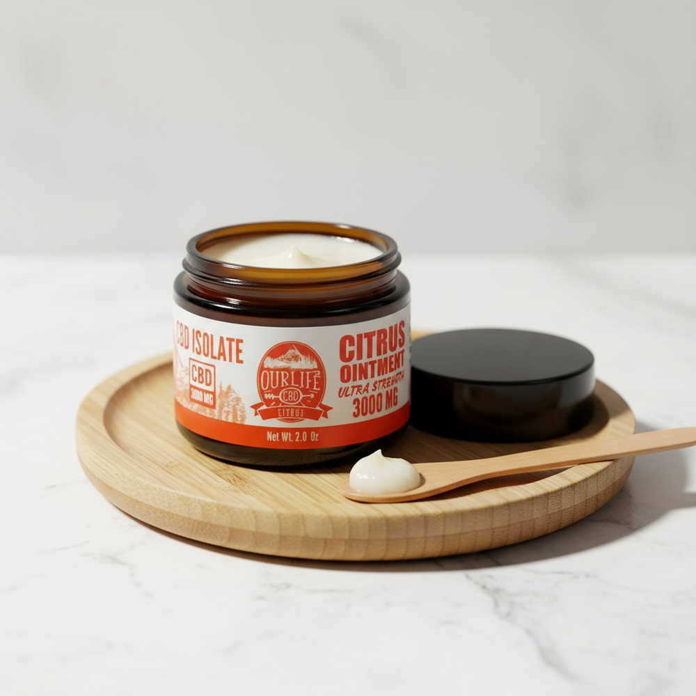 Jar of citrus ointment with a wooden spoon and lid on a white background