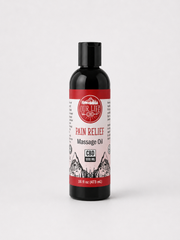 A bottle of Our Life CBD Pain Relief Massage Oil on a light gray background. The bottle is black with a black cap and features a white and red label with a mountain graphic.